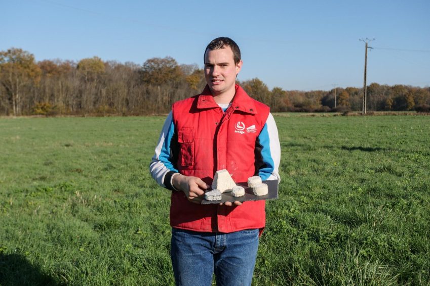 Homme dans un champ qui présente ses fromages de chèvre.
